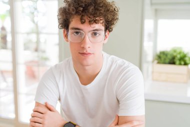 Gevşek ciddi ifade ile yüzünde gözlüklü genç yakışıklı adam. Basit ve çapraz silah ile doğal