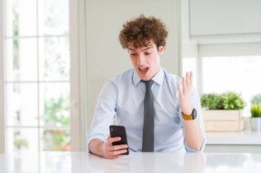 Kocaman bir gülümseme ile çığlık zaferini kutluyor office çok mutlu ve heyecanlı, kazanan ifade, smartphone kullanarak ve ellerini kaldırdı genç iş adamı