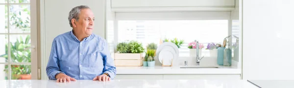 Wide angle perspective of handsome senior man at home looking to side, relax profile pose with natural face with confident smile.