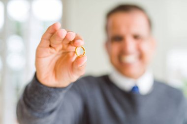 Bir nişan yüzüğü tutarak ve gülümseyen orta yaş adam yakın çekim
