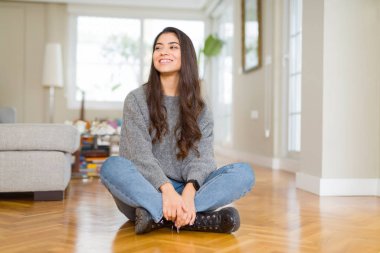Ev uzak tarafına gülümseme ile yüzünde, doğal ifade arıyorum, yerde oturan genç güzel kadın. Kendine güvenen gülüyor.