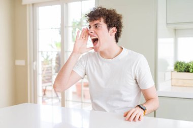 El ağızdan bağırarak ve ile yan için çığlık evde beyaz t-shirt giyen genç yakışıklı adam. İletişim kavramı.