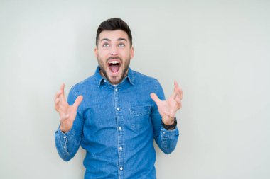 Genç yakışıklı adam izole arka plan çılgın ve kızgın bağırarak ve agresif ifade ve silah kaldırdı bağırıyor. Hayal kırıklığı kavramı.