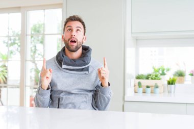 Yakışıklı adam evde hayret ve yukarıya bakıp parmakları ile işaret şaşırttı ve silah kaldırdı.