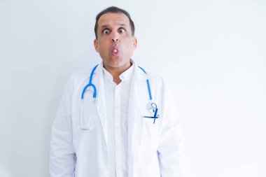 Orta yaş doktor beyaz arka plan yapma balık yüzüne dudaklı, çılgın ve komik bir jest stetoskop ve tıbbi ceket giyen adam. Komik ifade.