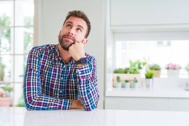 Çene düşünme hakkında soru, dalgın ifade üzerine el ile renkli gömlek giymiş yakışıklı adam. Düşünceli yüzüyle gülümsüyor. Şüphe kavramı.