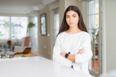 Genç güzel kadın evde beyaz masa şüpheci ve sinir, onaylamayan ifade yüz çapraz kolları üzerinde. Negatif kişi.