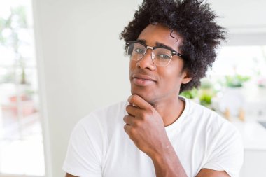Afrika kökenli Amerikalı adam gözlüklü el ile çene düşünme hakkında soru, dalgın ifade üzerine. Düşünceli yüzüyle gülümsüyor. Şüphe kavramı.