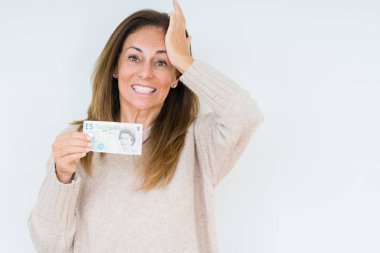 5 pound banknot kafasına, el ile vurguladı izole arka plan üzerinde tutan orta yaş kadın şok utanç ve sürpriz suratla, öfkeli ve sinirli. Korku ve hata için üzgün.