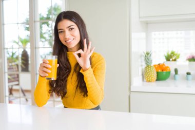 Genç kadın parmakları, mükemmel sembolü olan ok işareti yapıyor taze portakal suyu bir bardak içme