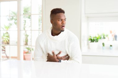 Yakışıklı Afrikalı-Amerikalı adam beyaz masaya elini karnına ile çünkü mide bulantısı, ağrılı hastalık hasta hissediyor. Ağrısı kavramı.