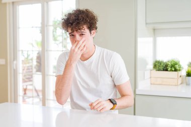 Ev kokulu, beyaz t-shirt pis ve iğrenç bir şey, dayanılmaz koku, holding nefes parmak ile burun üzerinde giyen genç yakışıklı adam. Kötü kokuyor kavramı.