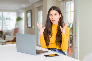 Bilgisayar dizüstü çılgın ve kızgın bağırarak ve agresif ifade ve silah kaldırdı bağırmaya kullanan genç kadın. Hayal kırıklığı kavramı.