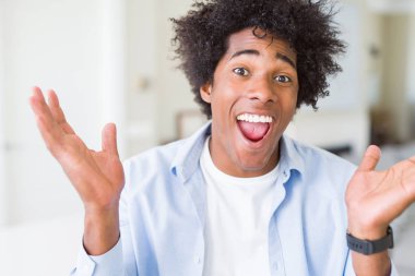 Afrika kökenli Amerikalı adam evde çılgın ve başarı için hayran kaldırdı Kollarını açarak kutluyor ve heyecanlı çığlık gözleri açık. Kazanan kavramı