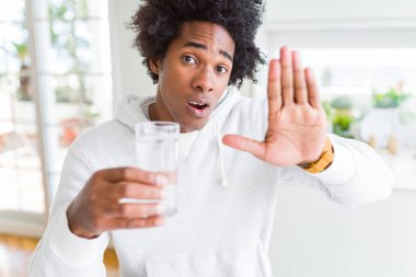 Afrika kökenli Amerikalı adam ile evde su içme dur işareti ile ciddi ve kendine güvenen ifade, savunma hareketi yaparken el açmak
