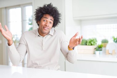 Afrikalı-Amerikalı adam evde clueless ve şaşkın bir ifadeyle kollar ve eller kaldırdı. Şüphe kavramı.