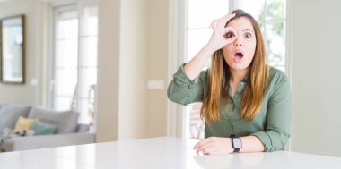 Güzel genç kadın evde ok jest sürpriz yüz, göz parmaklarının arasından seyir şok yapıyor. İmansız ifade.