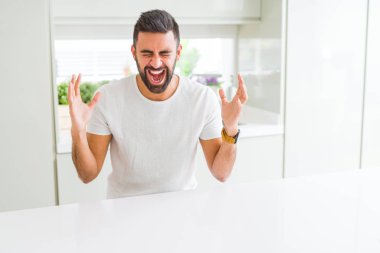 Yakışıklı İspanyol casual beyaz t-shirt ev kızgın ve silah ile başarı için deli kutluyor, kaldırdı ve heyecanlı çığlık gözleri kapalı dostum. Kazanan kavramı