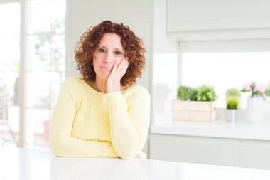 Sarı kazak düşünme seyir giyen güzel üst düzey kadın yorgun ve sıkılmış çapraz silah depresyon sorunları ile.