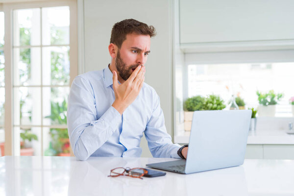 Handsome business man working using computer laptop cover mouth with hand shocked with shame for mistake, expression of fear, scared in silence, secret concept