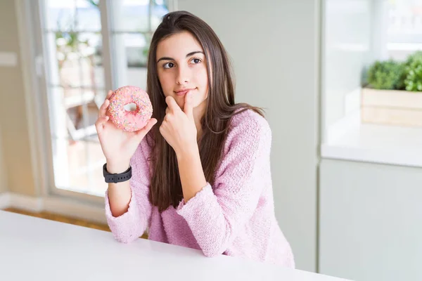 ピンクのチョコレートを食べて美しい若い女性チップに関する質問は 非常に混乱してアイデアを考えてドーナツ深刻な顔 — ストック写真