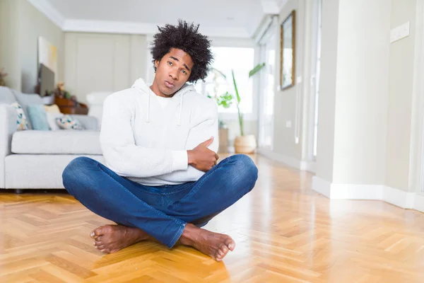 African American man sitting on the floor at home skeptic and nervous, disapproving expression on face with crossed arms. Negative person.