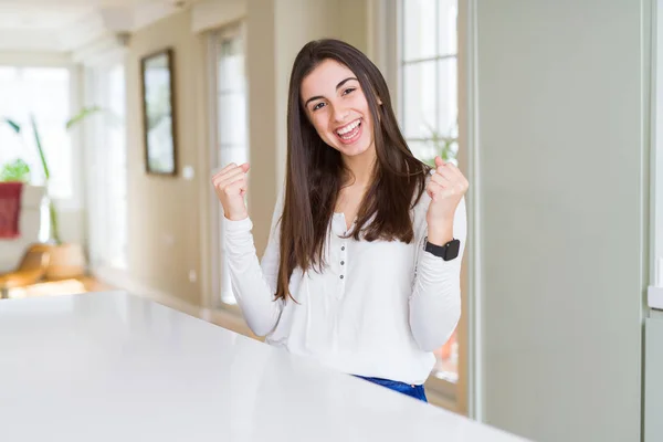 Hermosa Joven Sentada Mesa Blanca Casa Celebrando Sorprendida Sorprendida Por —  Fotos de Stock