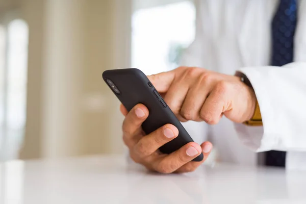 Закрыть руки врача среднего возраста с помощью смартфона — стоковое фото