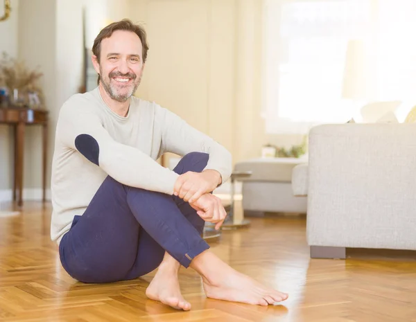 Bonito homem de meia idade sentado no chão sorrindo para o veio — Fotografia de Stock