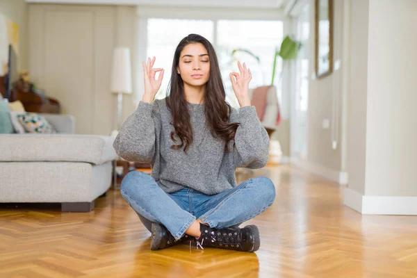 Young beautiful woman sitting on the floor at home relax and smiling with eyes closed doing meditation gesture with fingers. Yoga concept.