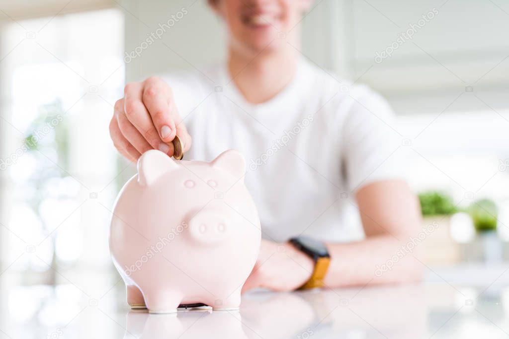 Close up of man putting a coin inside piggy bank as saving or in