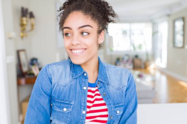 Afro saçlı rahat denim ceket görünümlü yan ve dik dik bakma uzağa düşünce gülümseyen güzel genç Afro-Amerikan kadın.