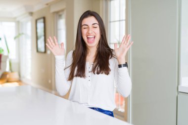 Evde beyaz masaya oturan güzel genç kadın deli ve çığlık kaldırdı ve kapalı gözleri heyecanlı silah ile başarı için deli kutluyor. Kazanan kavramı