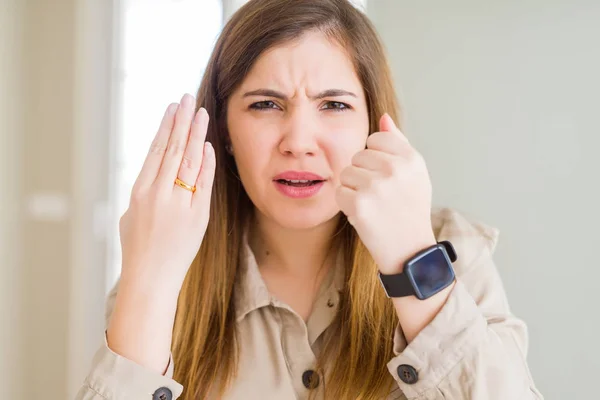 Beautiful young woman showing alliance ring on hand annoyed and frustrated shouting with anger, crazy and yelling with raised hand, anger concept