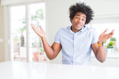 Afro-Amerikan iş adam clueless ve şaşkın bir ifadeyle kollar ve eller kaldırdı. Şüphe kavramı.