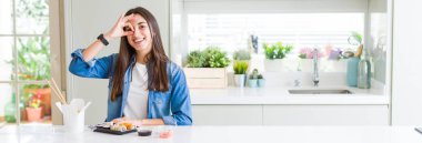 Güzel genç kadın gülümseyerek el parmakları ile mutlu yüz üzerinden seyir göz ile ok jest yapıyor teslim suşi yemek geniş açı resim.