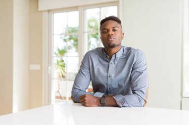 Afro-Amerikan yakışıklı yüzünde ciddi bir ifade ile beyaz tabloda gevşek. Basit ve doğal kameraya bakıyor.