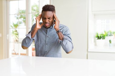 Yakışıklı Afrikalı-Amerikalı adam beyaz masaya baş baş ağrısı için el ile çünkü stres. Migren muzdarip.