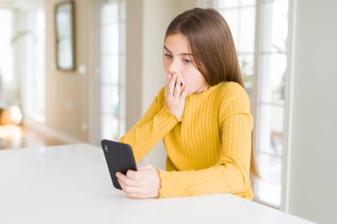 Güzel genç kız çocuk için hata, ifade korku, utanç ile şok el ile Smartphone kapak ağız kullanarak ileti gönderme sessizlik içinde gizli kavramı korkuttu