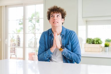 Casual denim ceket evde umut ifade yüzünde çok duygusal ve endişe ile birlikte yalvarıyor ve ile dua eller genç yakışıklı adam. Bağışlanmak. Din kavramı.