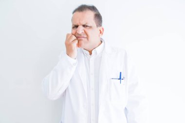 Orta yaş doktor adam stresli ve gergin ile beyaz arka plan üzerinde tıbbi bir palto giyiyor tırnak ısırma dudaklarından eller. Anksiyete sorunu.