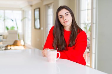 Yüzünde ciddi bir ifade ile siyah kahve içme güzel ve genç birbayan. Basit ve doğal kameraya bakıyor.