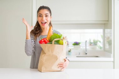 Kağıt torba yiyecek çok mutlu ve heyecanlı, tam büyük gülümseme ile çığlık ve ellerini kaldırdı kazanan ifade kutluyor zafer tutan genç kadın