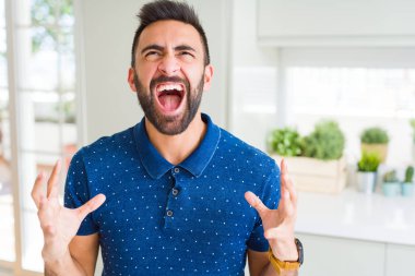 Yakışıklı İspanyol adam evde deli ve deli bağırarak ve agresif ifade ve silah kaldırdı bağırıyor. Hayal kırıklığı kavramı.