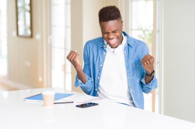 Afrika kökenli Amerikalı öğrenci adamım dizüstü bilgisayarlar kullanarak okuyan ve kulaklıklar giyen çok mutlu ve heyecanlı kazanan jest silah ile yapıyor, gülümseyerek ve başarı için çığlık kaldırdı. Kutlama kavramı.