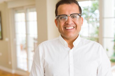 Evde kameraya gülümseyen gözlük takan orta yaş erkek