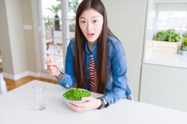 Taze yeşil bezelye bir sürpriz yüz, korkuyor ve heyecanlı korku ifadesi ile şok korkmuş yemek güzel Asyalı kadın