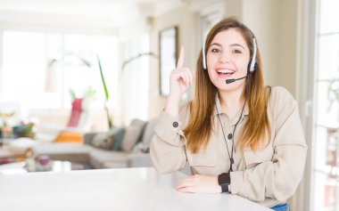 Kulaklık, office işaret parmağı ile başarılı fikir giyen güzel genç operatör kadın. Çıktıktan ve mutlu. Bir numara.