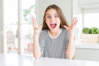 Giyen güzel genç kız çocuk t-shirt kutluyor deli çizgili ve çığlık kaldırdı ve açık gözleri heyecanlı silah ile başarı için hayrete düşürdü. Kazanan kavramı