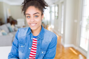 Yüzünde mutlu ve güzel bir gülümseme ile rahat denim ceket giyen afro saçlı güzel genç Afro-Amerikan kadın. Şanslı kişi.